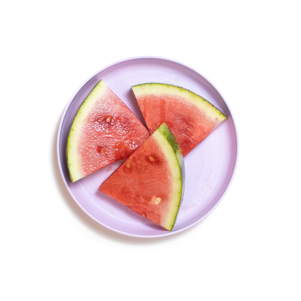 A purple plate with three wedges of watermelon.