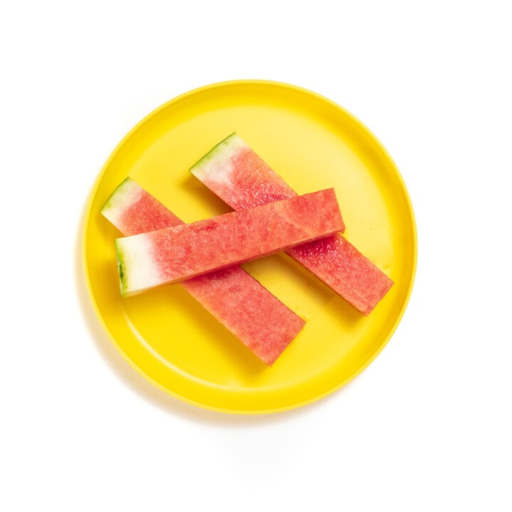 Yellow plate with sticks of watermelon.