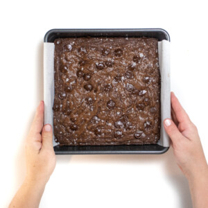 Hands holding a baked tray of brownies.