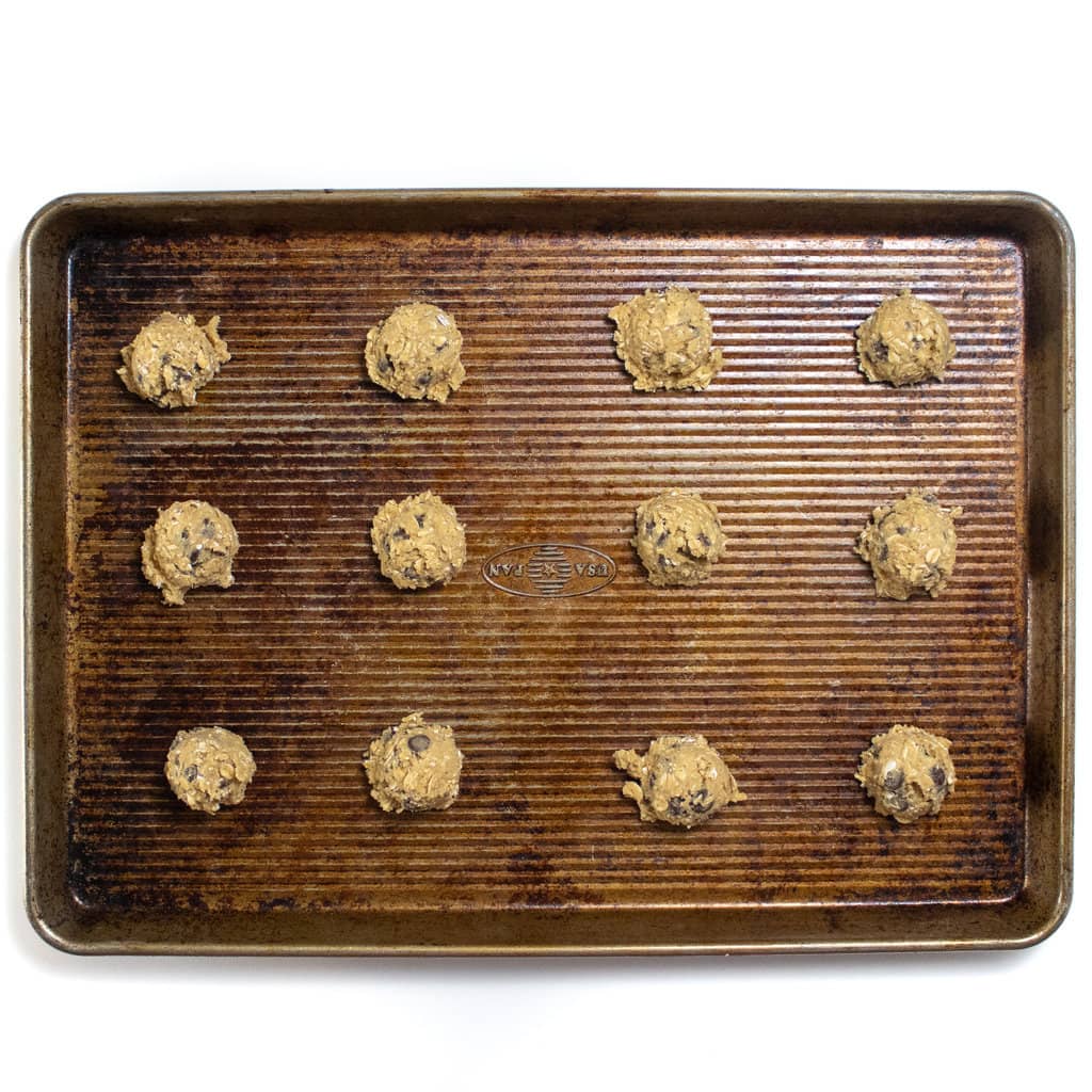 A used baking sheet with drops of lactation cookies on it.