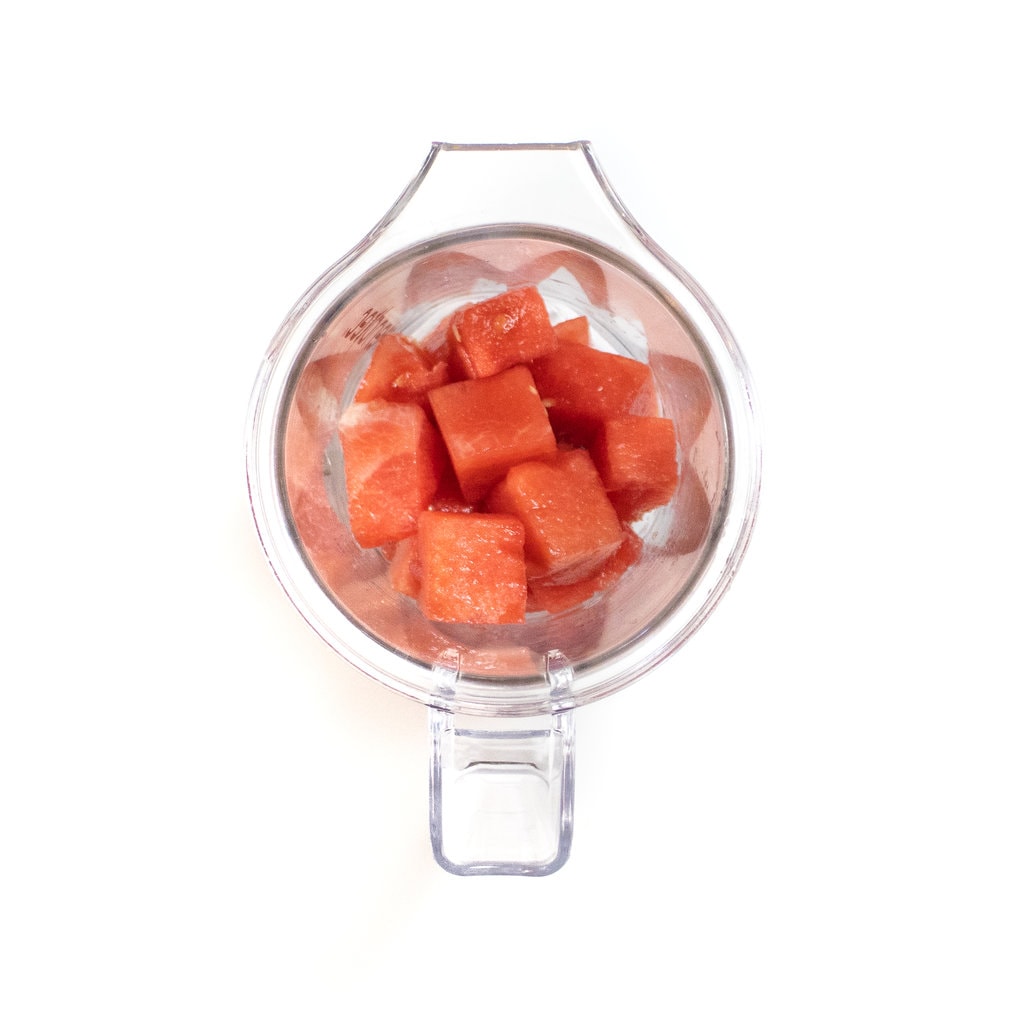 A clear blender with chunks of watermelon inside.