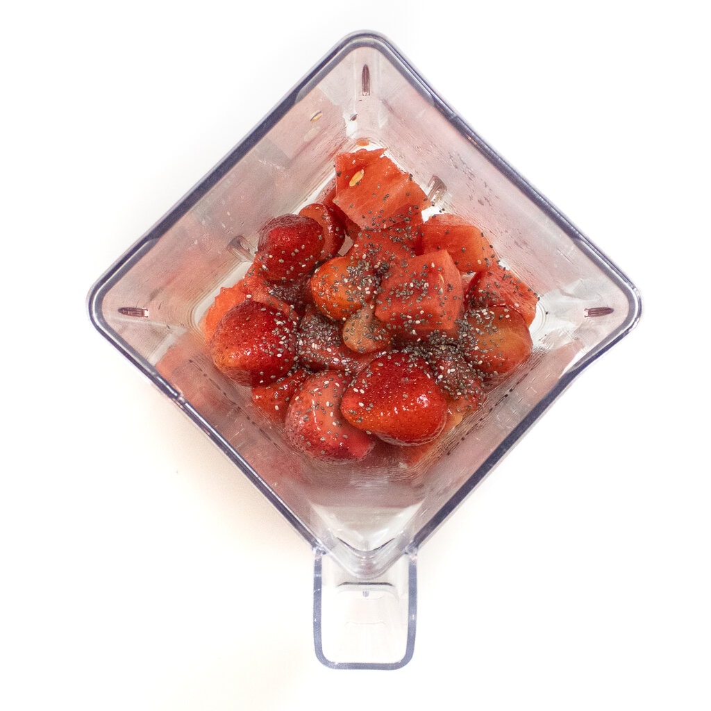 Clear blender on a white background with watermelon frozen strawberries, Chia seeds and my juice.