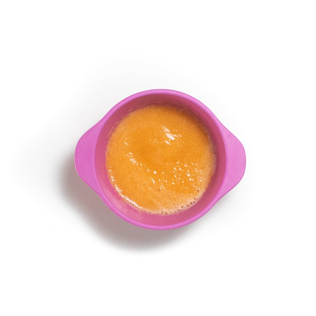 A pink baby bowl with a smooth cantaloupe purée.