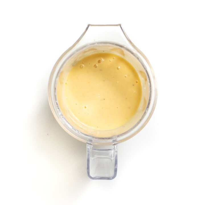 A clear blender with puréed cantaloupe, yogurt and bananas.