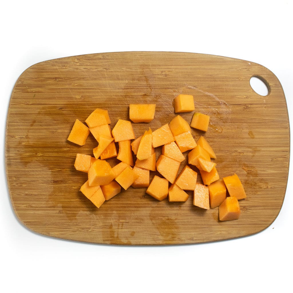 Cubes of cantaloupe on a wooden cutting board.