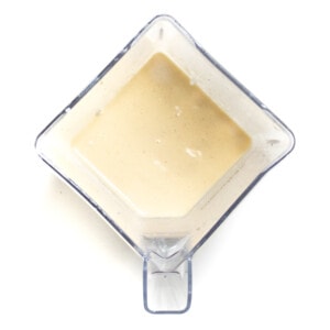 A clear blender with a creamy light yellow smoothie.