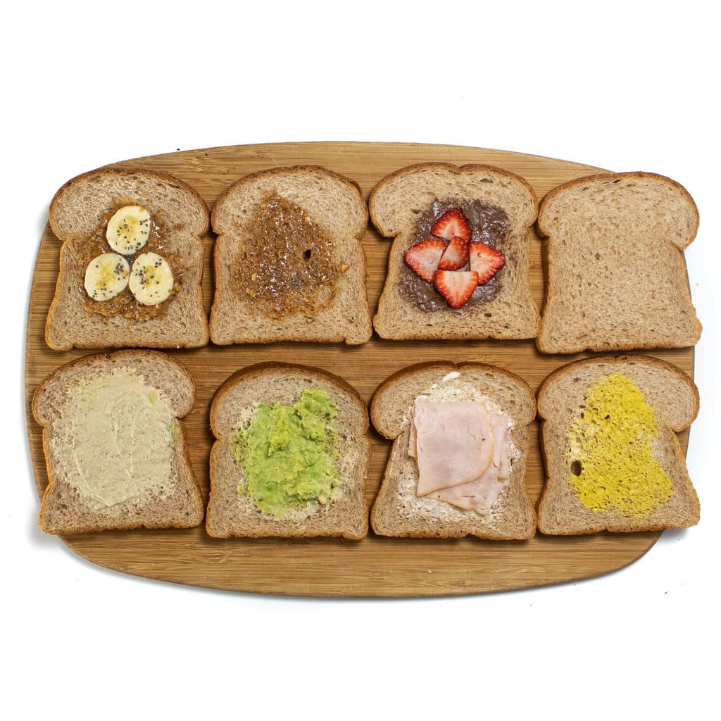 Eight pieces of bread with different toppings for kids lunches with uncrustables.