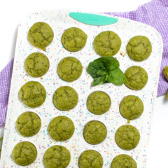 A colorful muffin tin with spinach muffins against a white background with a purple navigating.