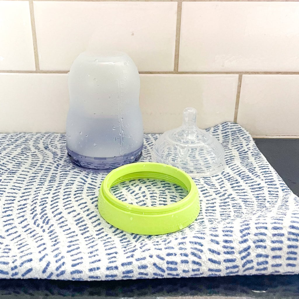 A comotomo bottle and parts drying next to a sink on a counter.