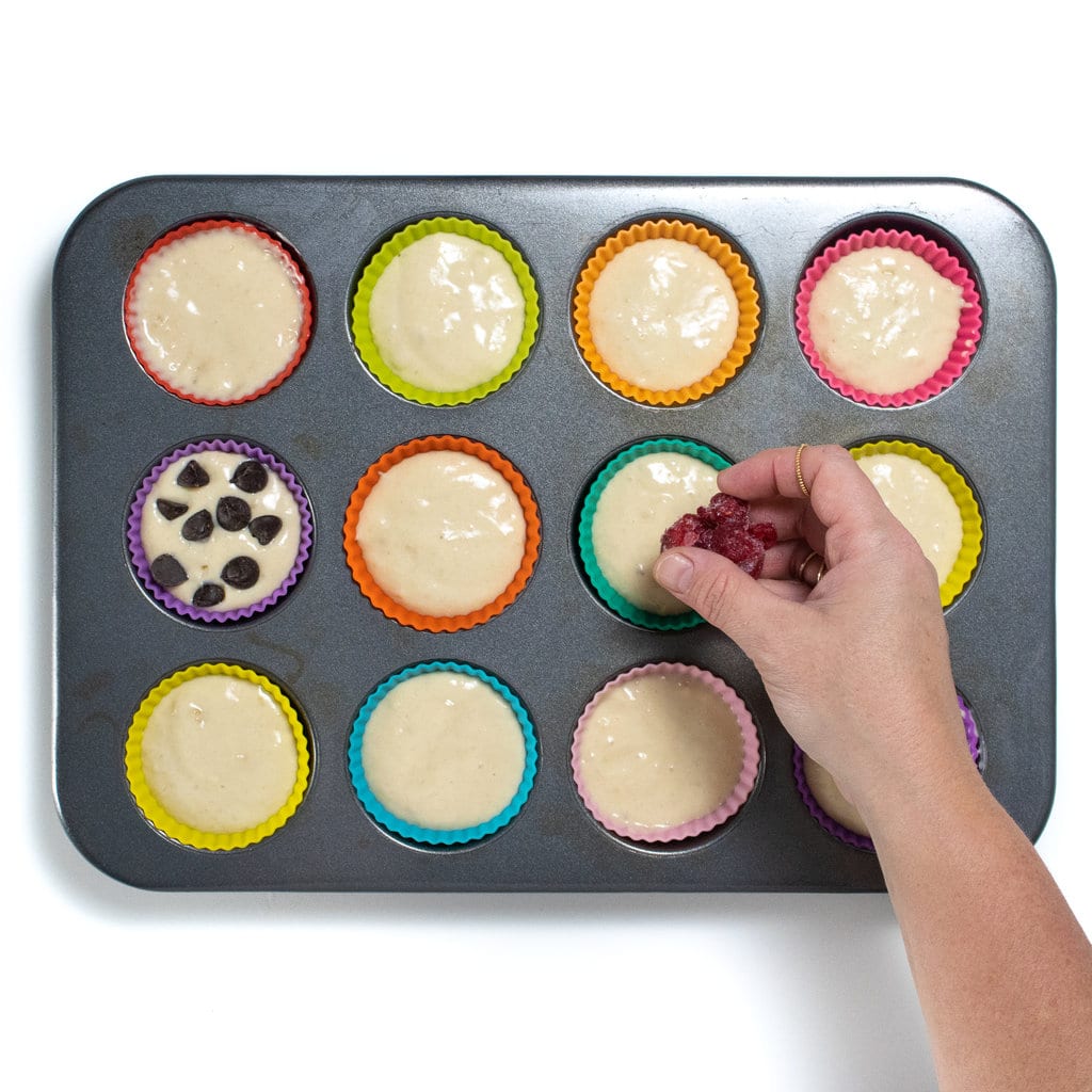 A muffin tin with pancake muffin batter and colorful muffin cups.