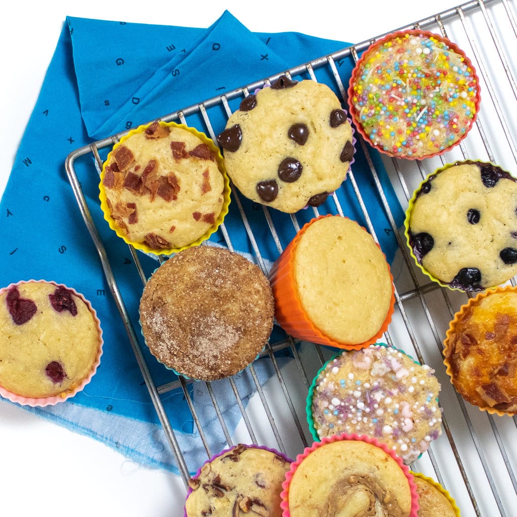 A cooling rack with pancake muffins with different toppings against a white background with blue napkin.