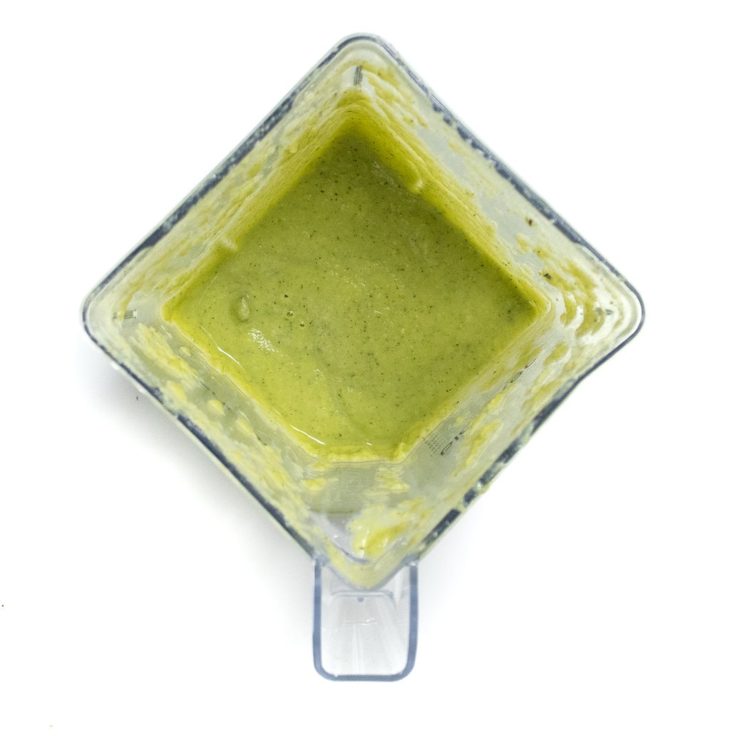 A blender with zucchini and cauliflower baby food purée against a white background.