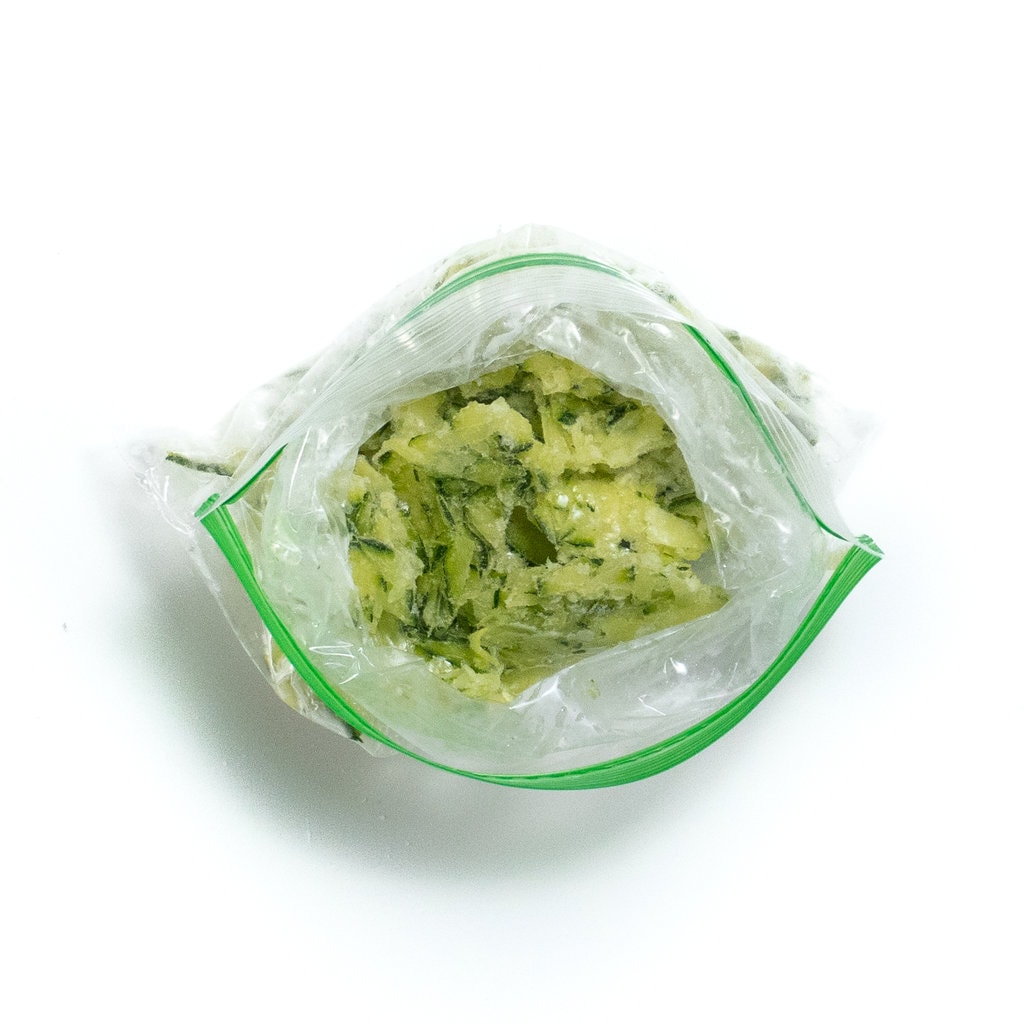 A top view of a baggie full of grated zucchini.