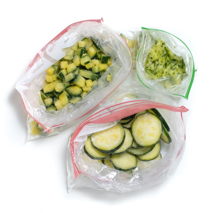 Three Ziploc bags full of frozen zucchini three different ways.