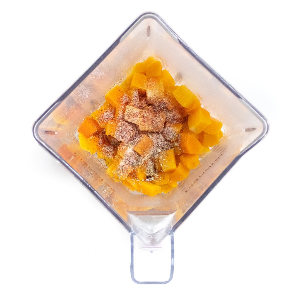 A blender full of cooked butternut squash and spices.
