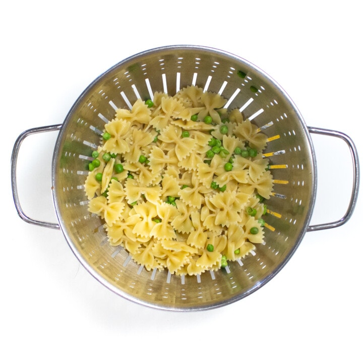 Colander filled with cooked pasta and peas
