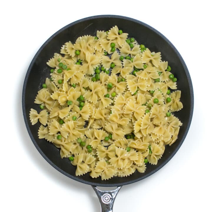 Skilled with cooked pasta and peas against a white background.