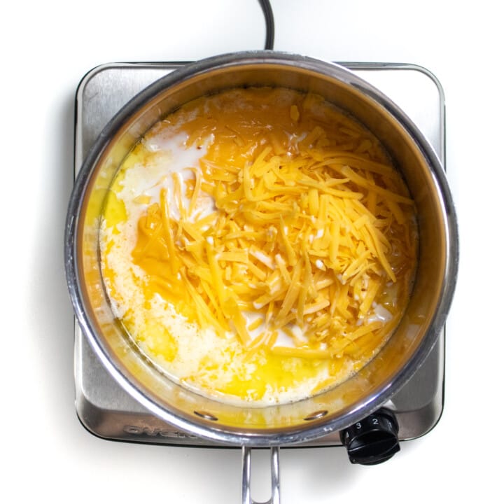 Silver sauce pan with sweet potato purée, butter and cheddar cheese.