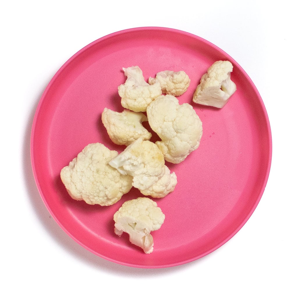A pink plate with cauliflower florets.