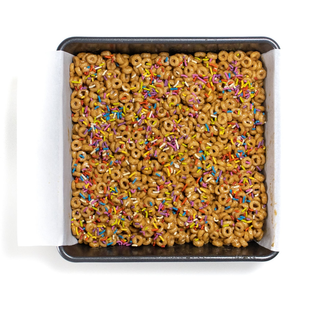 A baking dish bowl of cereal bars with sprinkle on top.