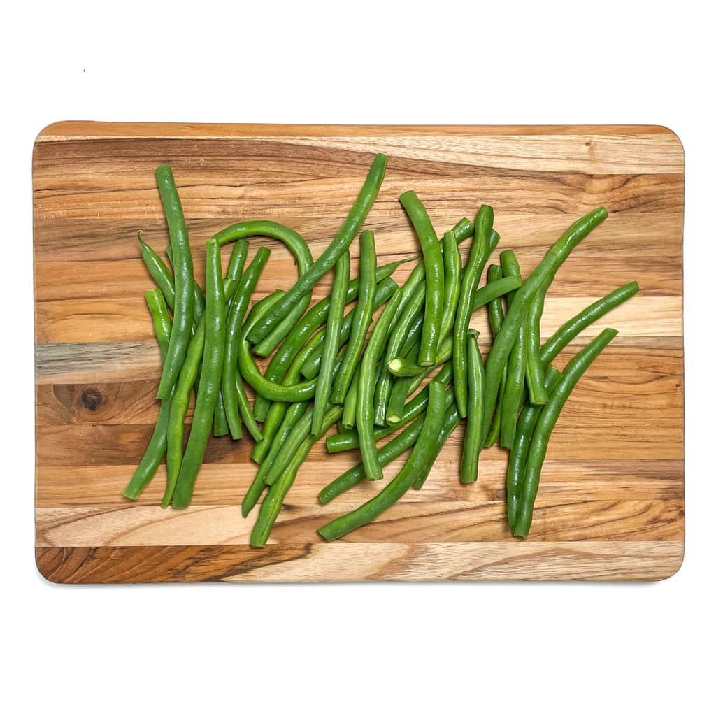Cutting board filled with trimmed green beans.