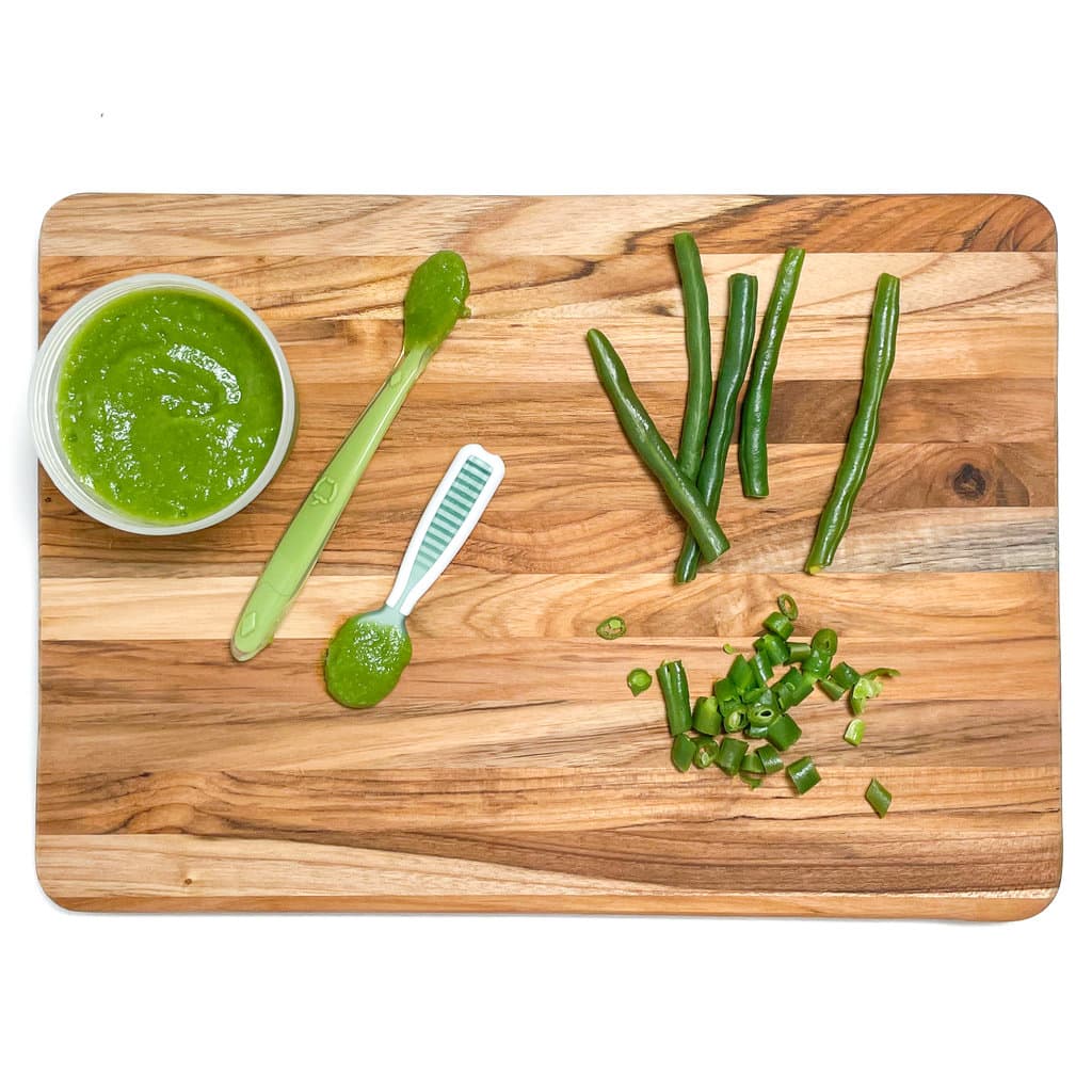 Wooden cutting board showing different ways to serve green beans to baby.