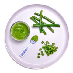 Purple baby plate filled with different ways to serve green beans to baby - whole, chopped or as a puree.
