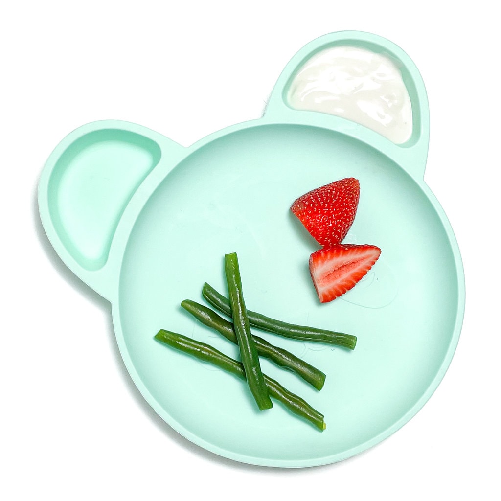 Baby plate with steamed green beans, strawberries and a side dip of yogurt.