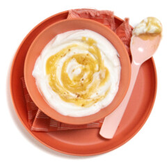 A pink bowl and plate with a pink spoonful of apple yogurt with a pinch of cinnamon on top.