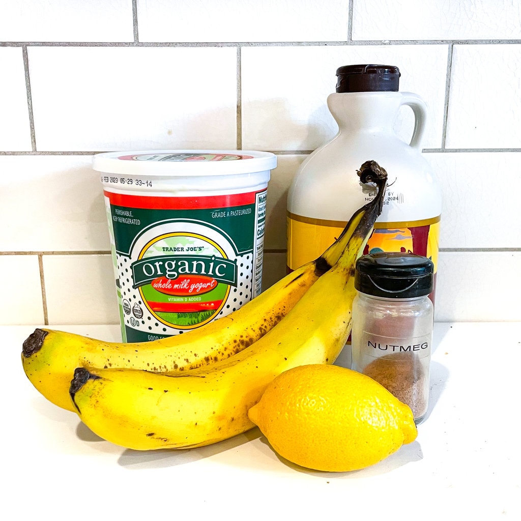 A white kitchen with ingredients for banana yogurt on it. 
