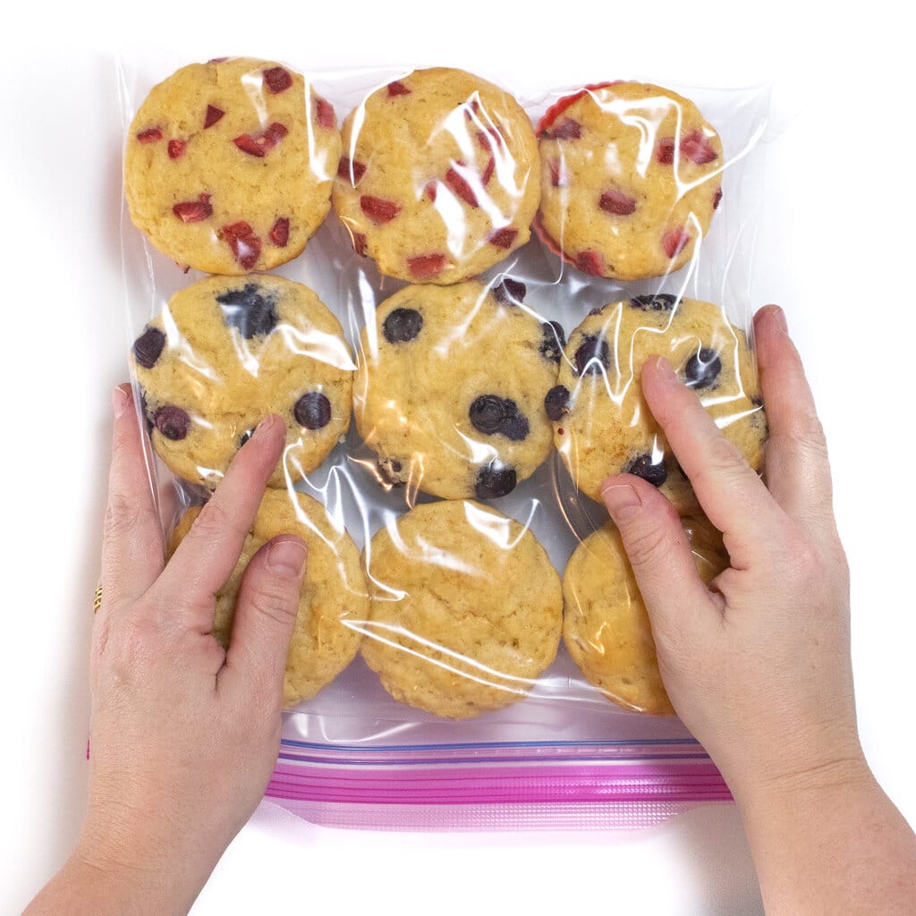 Two hands gently pressed in the air out of Ziploc bag full with freshly made homemade muffins.