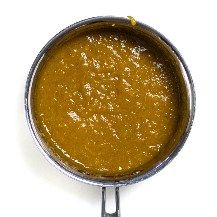 A simmered and puréed mango purée made with mango, nutmeg and maple syrup against a white background.