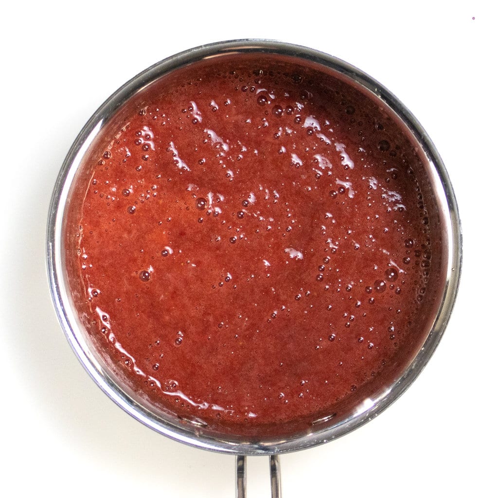 Silver saucepan with strawberry puree or compote inside.