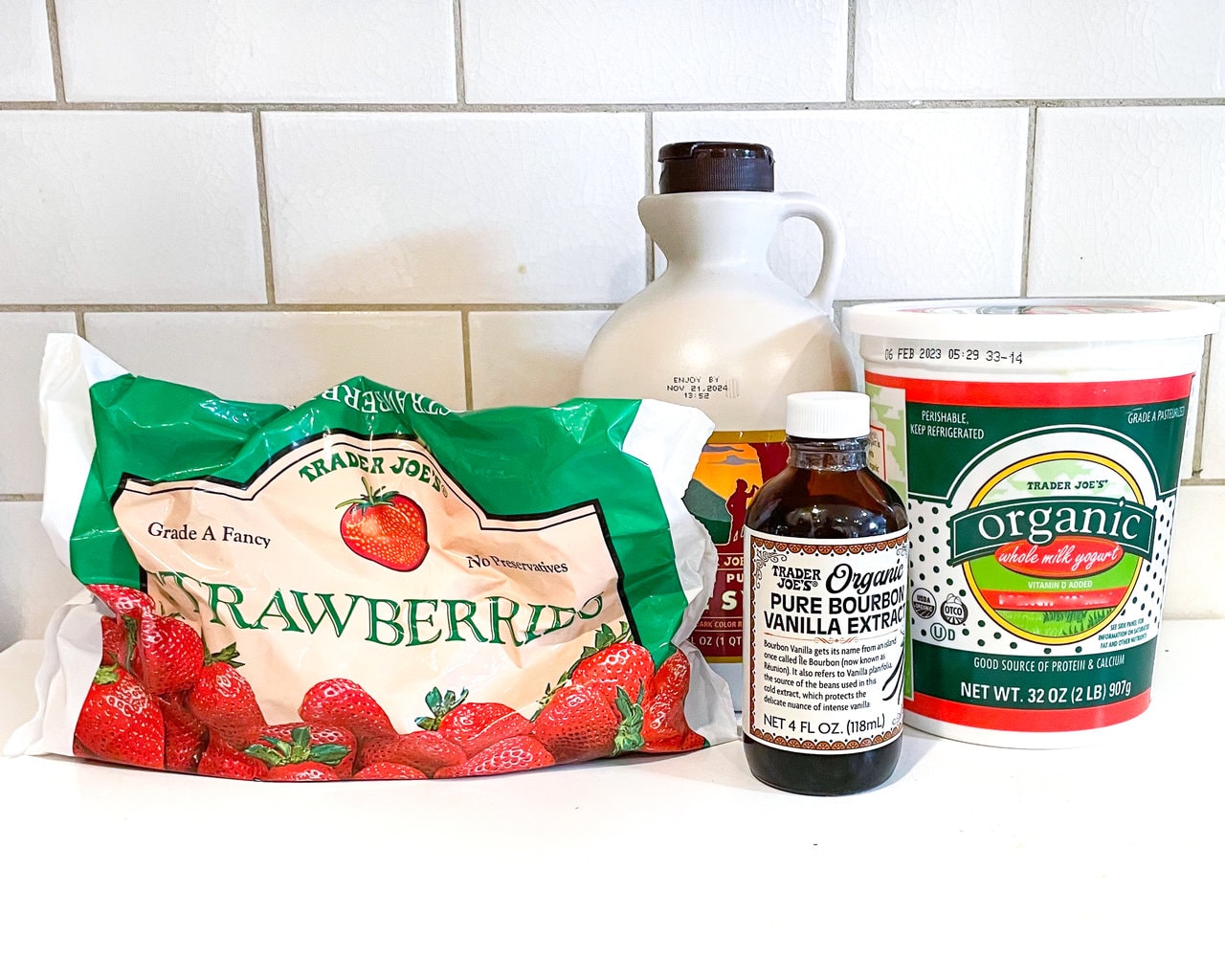 White kitchen counter with ingredients to make strawberry yogurt. 
