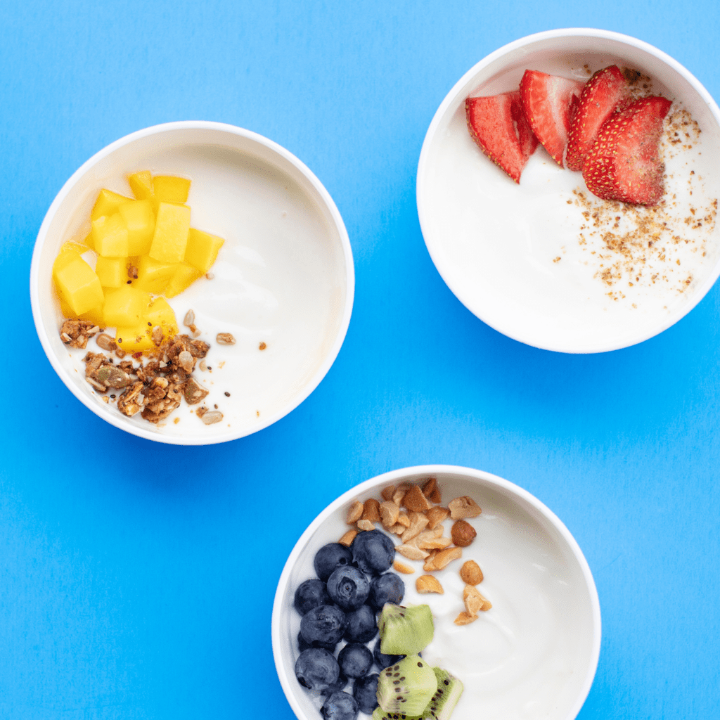 Three white bowls full of different toppings against the blue background.