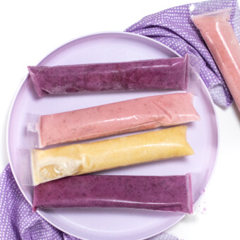 A purple kids played with three different colors of yogurt tubes that have been frozen.