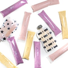 A white background with different flavored yogurt tubes and pouches scattered about.