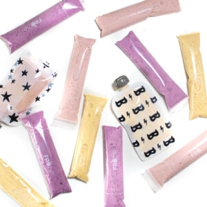 A white background with different flavored yogurt tubes and pouches scattered about.