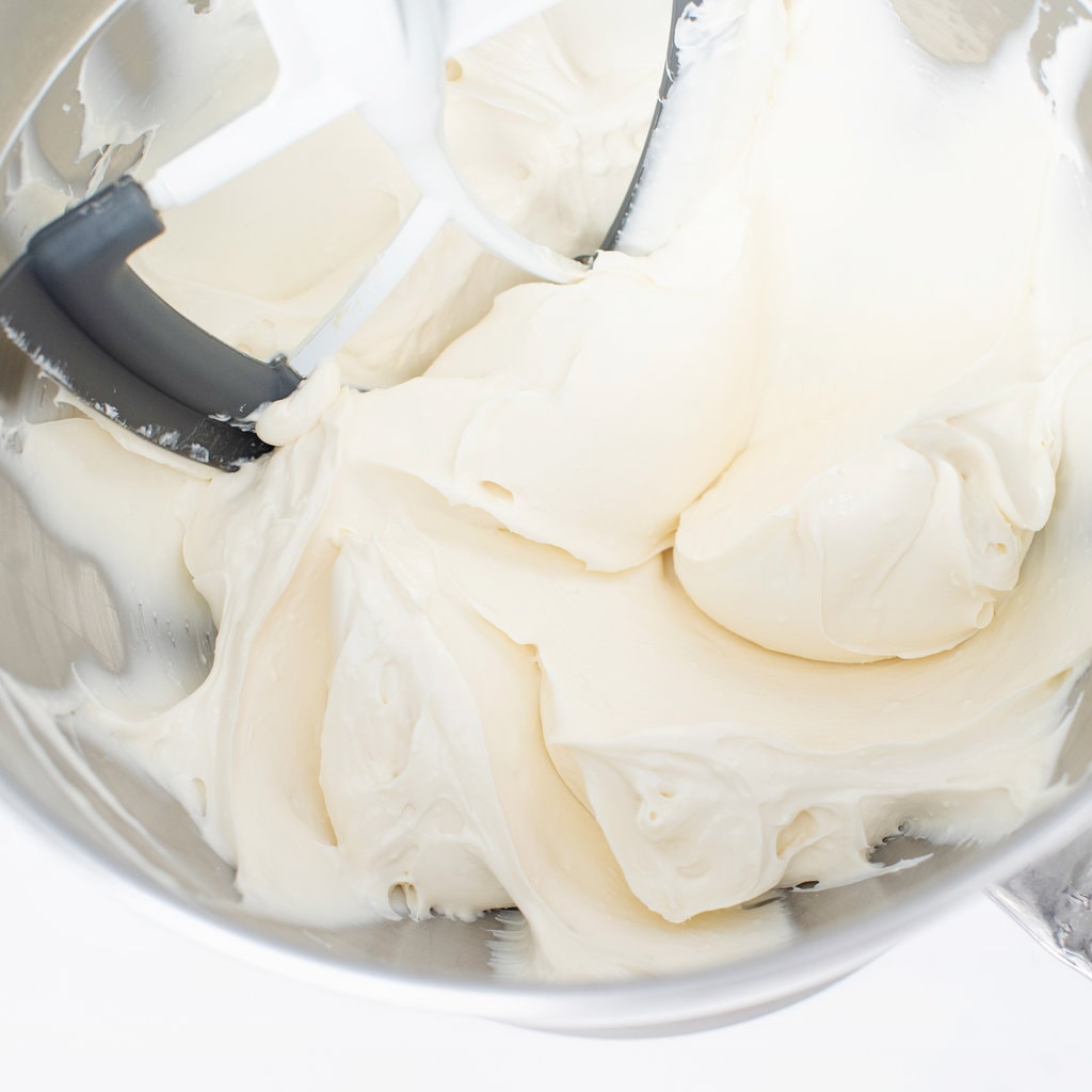 Silver mixing bowl with smooth and creamy cream cheese frosting.