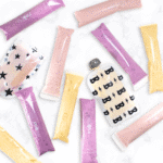 three different flavors of homemade yogurt tubes and pouches sitting on a white marble counter.