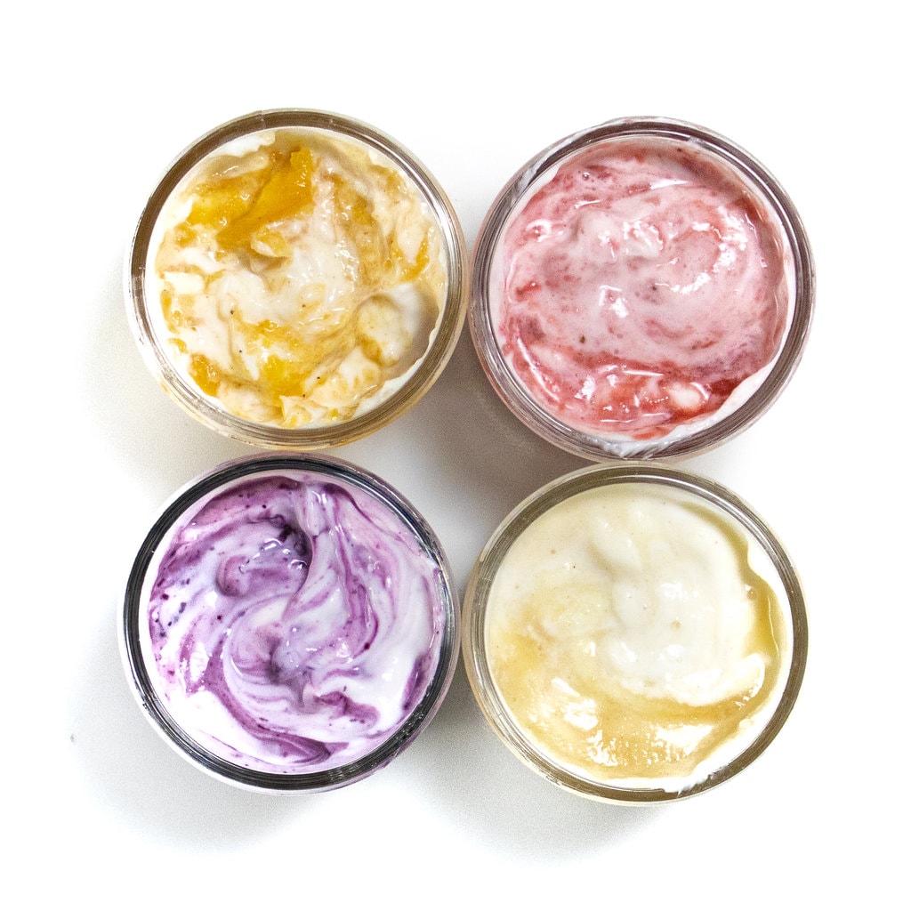 FOR A GLASS JARS FULL OF FRUIT SWIRLED AND YOGURT IN DIFFERENT FLAVORS AND COLORS AGAINST A WHITE BACKGROUND.