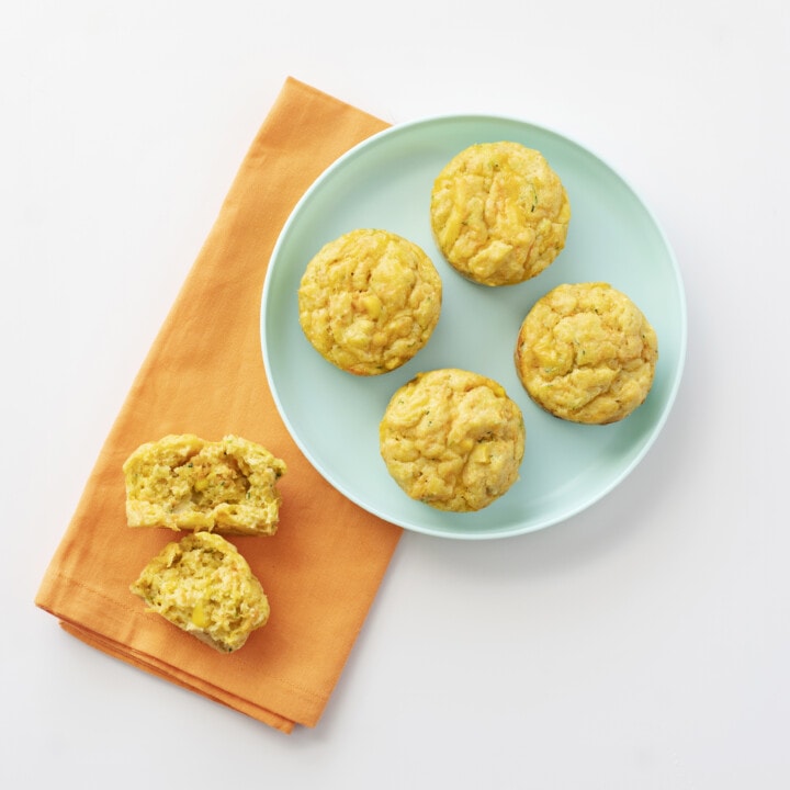 A blue plate with veggie muffins with an orange napkin.