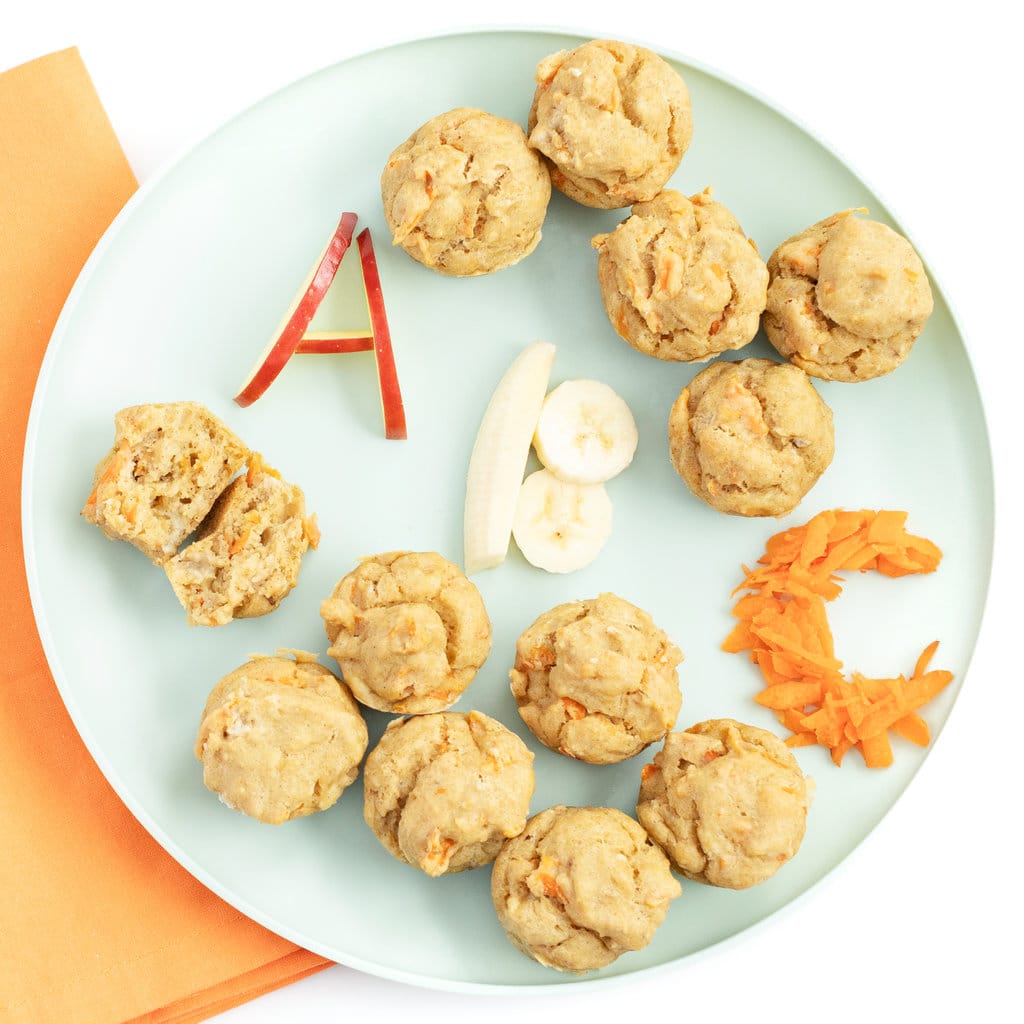 Teal kids play with ABC muffins with the letters a, B, C written out in Apple, banana and carrots again say marble background with a orange napkin.