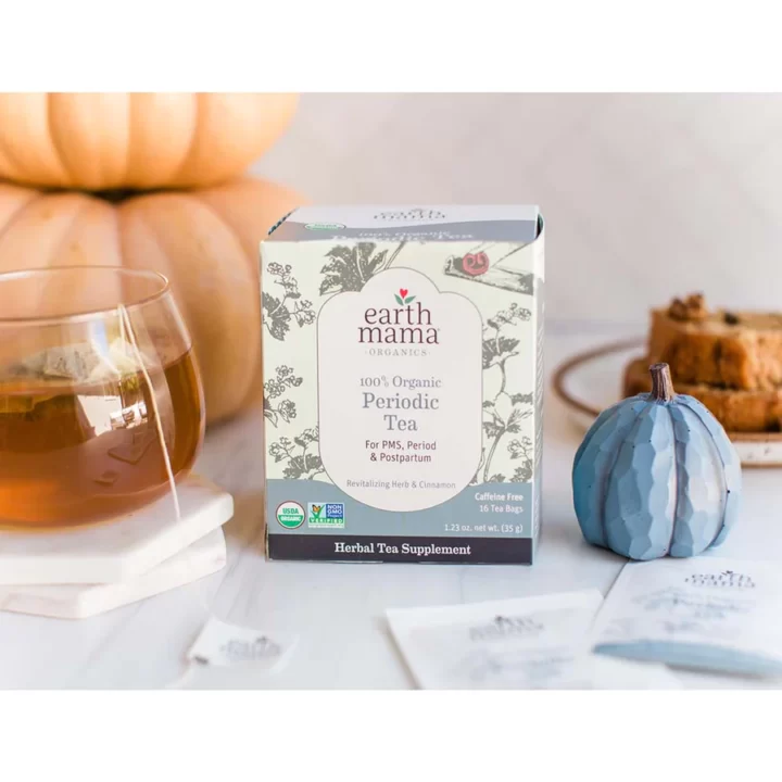 box of tea on a marble counter with a cup of tea simmer next to it and calm props behind it. 