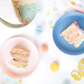 Spread of a smash cake and she was like for the cake on a pink and blue kids plate with birthday decorations in pastel colors spread around a white background.