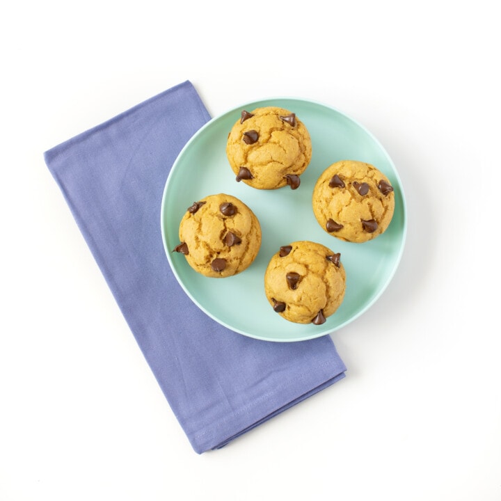 Teal kids plate with 4 sweet potato muffins with a blue napkin behind it.