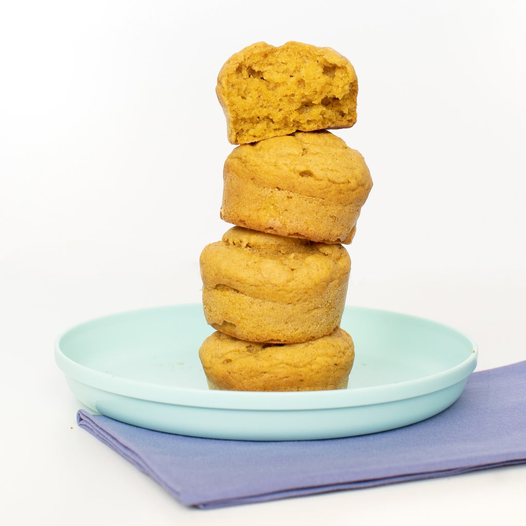 Teal kids plate and dark blue napkin against a white background - with a tower of stacked sweet potato muffins.