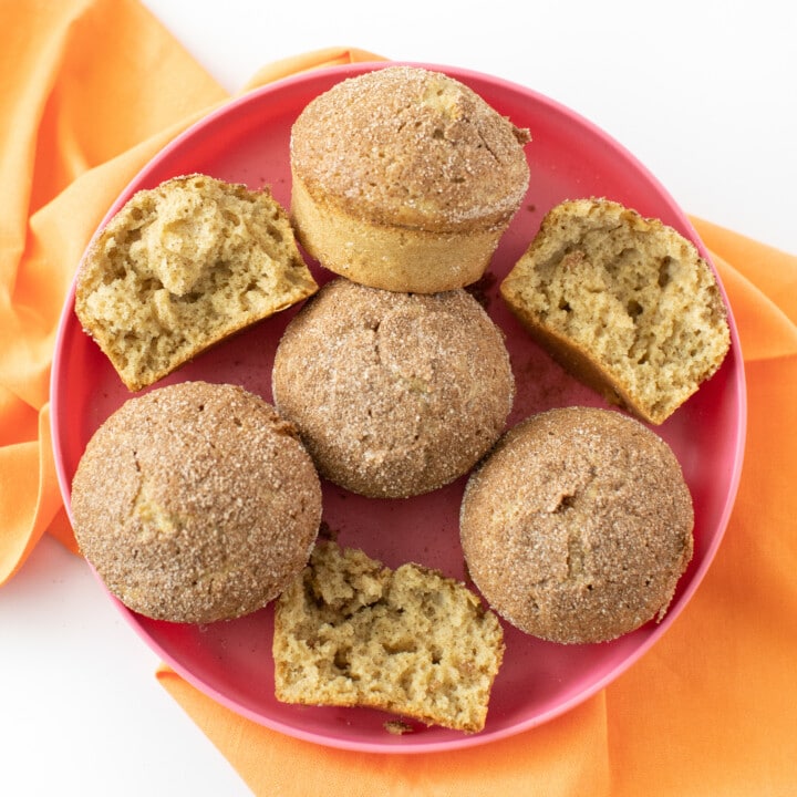 A colorful kids plate full of cinnamon muffins with a orange napkin.