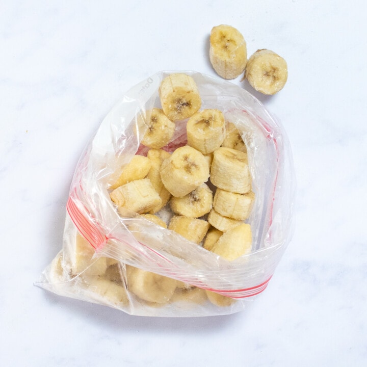 Ziploc bag full of slices of frozen banana on a white counter top.