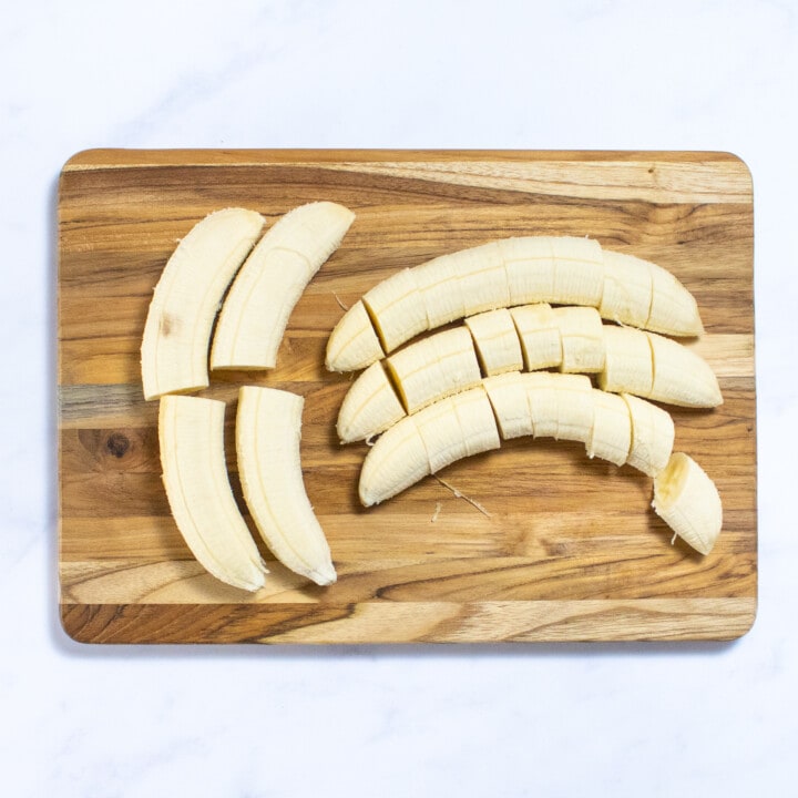 Bored on a white marble countertop with banana slices and bananas cut in half.